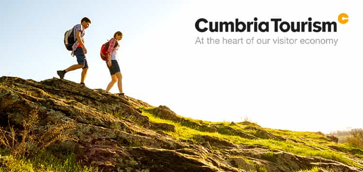 A couple hiking in Cumbria county with the Cumbria Tourism logo