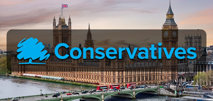 An image of the UK Houses of Parliament at dusk, with the River Thames and Westminster Bridge in the foreground. The iconic Big Ben clock tower is visible on the right side of the image. The sky is a mix of soft pink and blue hues. Superimposed over the image is the logo of the Conservative Party, featuring a stylised blue tree, and the word "Conservatives" in bold blue letters. Red double-decker buses and other vehicles are seen crossing the bridge, adding a dynamic element to the scene.
