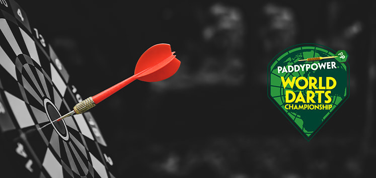 The image features a close-up of a dartboard with a red dart hitting the bullseye, symbolising precision and accuracy. To the right of the dartboard is a logo for the "Paddy Power World Darts Championship." The logo is green and shaped like a shield, with a dart integrated into the design. The dark background makes the red dart and the logo stand out prominently. The image conveys the excitement and competitive spirit of the World Darts Championship.