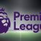 The image shows the Premier League logo, featuring a stylized lion's head wearing a crown on the left, with the text "Premier League" written in bold purple letters next to it. The background depicts a floodlit football pitch, suggesting a night match setting. The overall theme conveys the official branding of the English Premier League, the top-tier football competition in England.