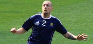 Alan Hutton playing for the Scotland national team, focused on the ball during an international match.