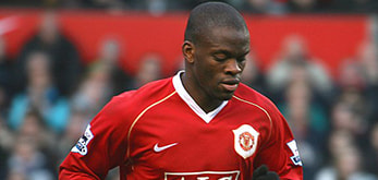 Image of a Louis Saha wearing a Manchester United jersey during a match, with the stadium crowd visible in the background.